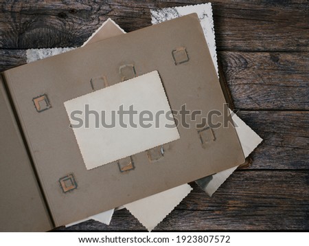 Clear blank photo frames to placed your pictures or text on old family album on wooden board background in retro style. Family traditions, memory and nostalgia concept. Antique album with old photos