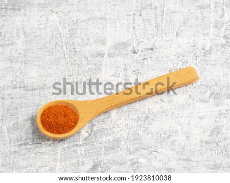 Spice red chili pepper in wooden spoon on a white concrete background. Diet and weight loss concept
