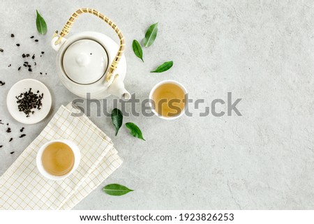 Herbal tea with two white tea cups and teapot, with green tea leaves. Flat lay, top view. Tea concept Royalty-Free Stock Photo #1923826253