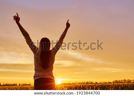 Young woman feeling victorious facing the beautiful sunset. Royalty-Free Stock Photo #1923844700