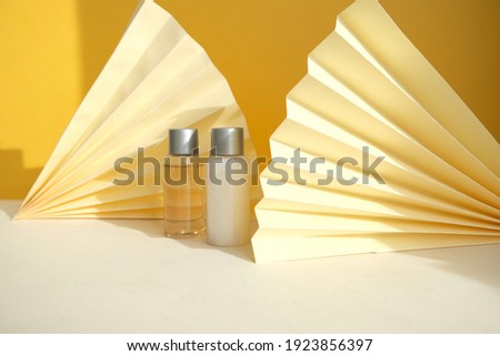 Set of two bottles (Body and hair care set) on geometrical background with paper fans.Mockup for product demonstration. 