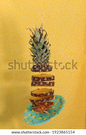Pineapple cut into plates falls down. Cut pineapple on yellow background.