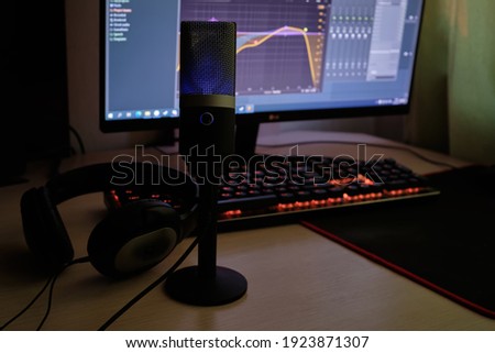 Blue microphone and headphones  at audio recording. Close-up. Microphone on the background of blurred computer screen. Microphone in the foreground. 
