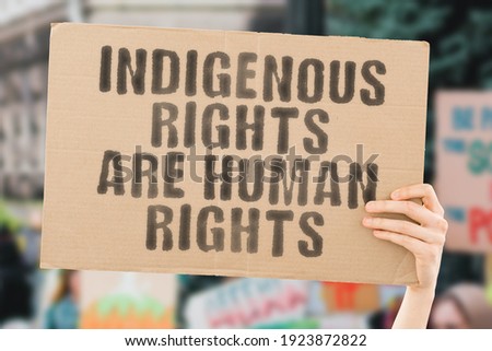 The phrase " Indigenous rights are human rights " on a banner in hand with blurred background. Protest. Rally. Land. Outdoor. Against. Law. Legislation. Control Royalty-Free Stock Photo #1923872822
