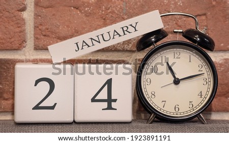 Important date, January 24, winter season. Calendar made of wood on a background of a brick wall. Retro alarm clock as a time management concept.