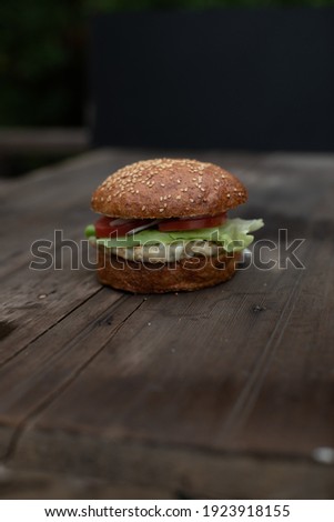 Fish burger on wooden table, dark tones 