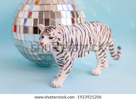 Plastic toy white tiger as a symbol of the new year 2022 on the Chinese calendar on a blue background with disco ball
