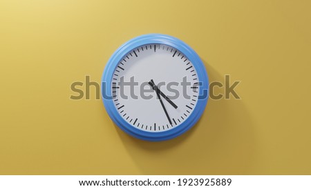 Glossy blue clock on a orange wall at twenty-six past four. Time is 04:26 or 16:26 Royalty-Free Stock Photo #1923925889