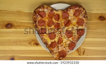 Heart shaped pizza for valentine's day. The camera approaches the pizza. View from above.