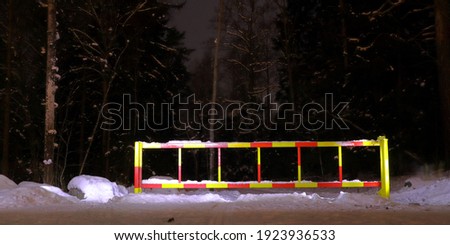 Night photo. A road stop or road block during the winter. Marked with red and yellow colors. Plenty of snow and trees. Long exposure shot. Stockholm, Sweden, Järfälla.