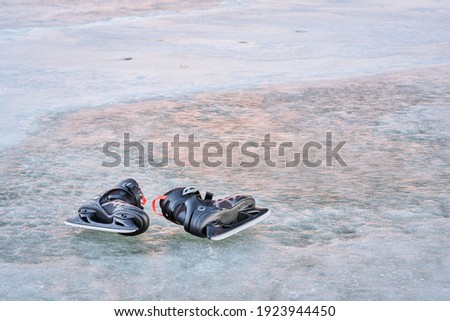 pair of men ice skates on a frozen lake with sunset reflections