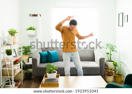 Playful man in his 30s dancing alone at home and having fun. Handsome man listening to music with headphones during a relaxing day Royalty-Free Stock Photo #1923951041
