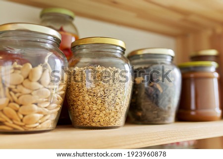 Kitchen pantry, wooden shelves with jars and containers with food, food storage. Jars with sunflower seeds, pumpkin seeds, oatmeal