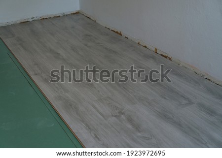 Worker installing modern wood laminate on the floor.