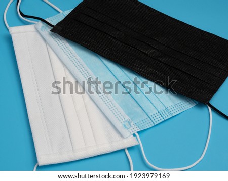 Close yo of three surgical masks of various colors on blue background. Safety and hygiene concept.