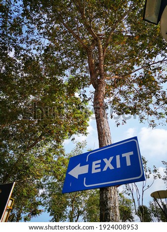 An exit signage with blue blackground and white frame. It was attached to a tree. This is an important signage for public as a guide during the tour. 