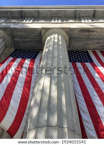 View from below of two large American flags hanging in front of the General Grant National Memorial aka Grant's Tomb in New York City, USA Royalty-Free Stock Photo #1924015541