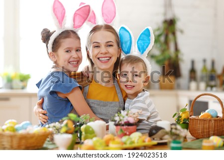 Happy easter! family mother and  cheerful children  with ears hare getting ready for holiday and smiling at camera