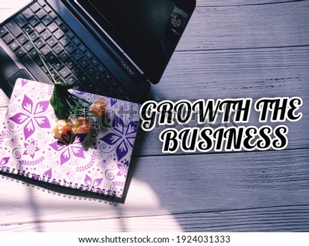 View of laptop, notebook and a bouquet of rose flower. With inscription "GROWTH THE BUSINESS". Business and education concept. Selective focus.