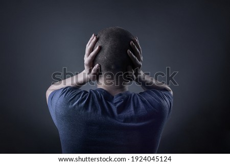 Teenage boy with his hands covering his ears and holding head Royalty-Free Stock Photo #1924045124