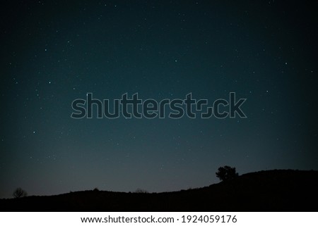 Photo of the stars with hills and tree silhouetted 