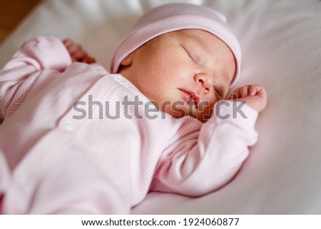 A newborn baby of less than a week in a pink jumpsuit sleeps on a white plaid. Cute Little Close.newborn photo shoot