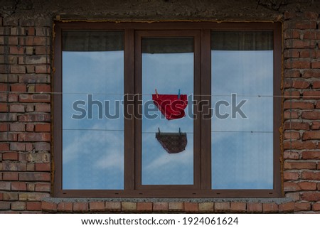 
Red women's lace panties hang on a rope on a window background