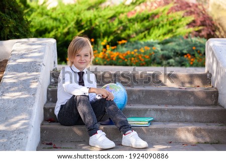 Cute schoolboy with books and globe on outdoors. Education for kids. Back to school concept