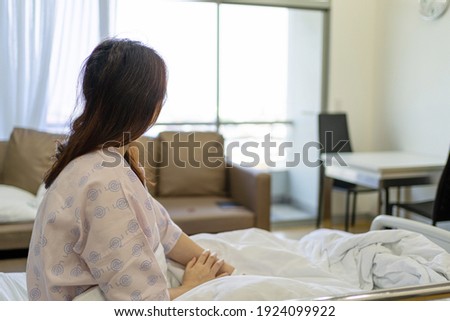 View of woman patient sitting on hospital bed and looking out of window and thinking something. Royalty-Free Stock Photo #1924099922