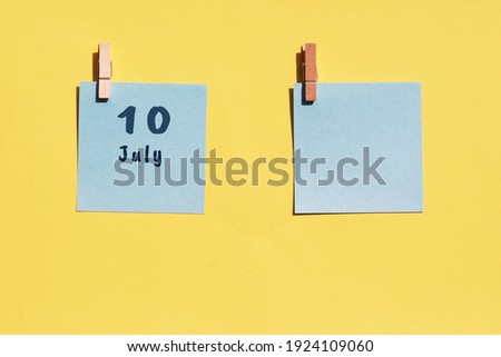 July 10st. Day of 10 month, calendar date. Two blue sheets for writing on a yellow background. Top view, copy space. Summer month, day of the year concept
