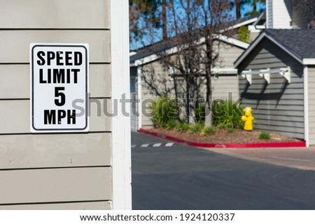 5 mph speed limit sign  in residential area. Blurred driveway in residential complex.