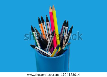 new bright colored pens and pencils lying in a penholder on a blue background. concept of office supplies. free space for advertising text Royalty-Free Stock Photo #1924128014