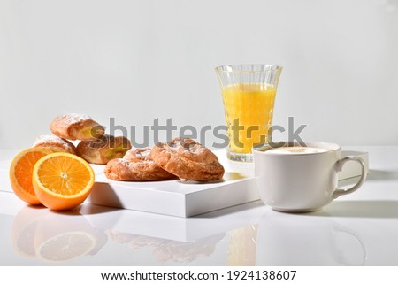 Traditional sweet pastries surrounded by a coffee cup, orange juice and an orange cut in half on a table. Traditional breakfast concept. Royalty-Free Stock Photo #1924138607