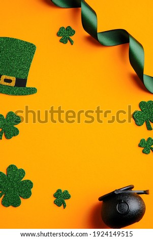 St Patricks day banner design. Top view pot of gold, shamrock leaves, leprechaun hat on orange background. Saint Patrick's day greeting card template.