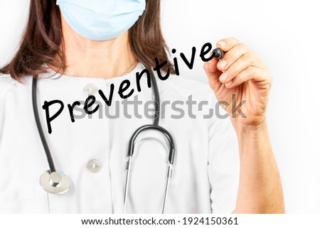 Doctor with mask writing the word preventive with a marker pen on a white background. Health concept