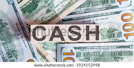 Concept words CASH on wooden blocks on a beautiful background from dollar bills.