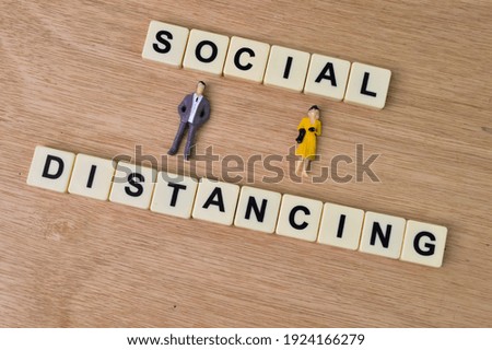 People miniatures and square letters with text SOCIAL DISTANCING