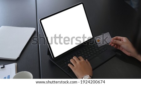 Close up view of businesswoman hands holding credit card and using computer tablet shopping online or internet banking.