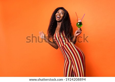 Photo of dark skin happy cheerful lady look empty space hold drink alcohol isolated on orange color background