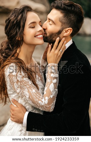 Beautiful wedding couple laugh and kiss on the background of stones. High quality photo Royalty-Free Stock Photo #1924233359