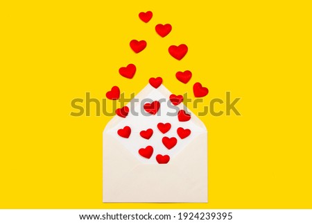 Valentine love day greeting card concept. Design of envelope and red hearts on yellow background top view. Flat lay.