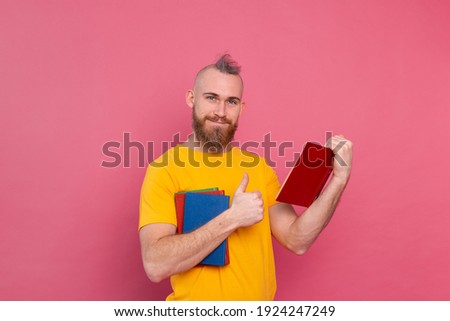 Bearded european man with stack of books on pink background