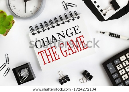 change the game. text on white notepad paper on light background near calculator, plant, table clock.