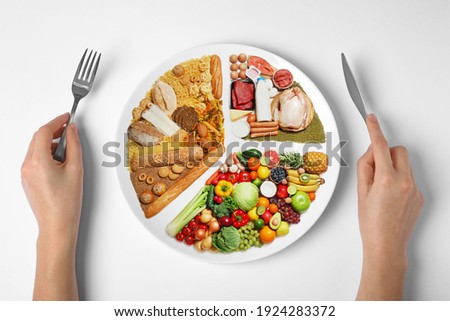 Woman holding cutlery near plate with different products on white background, top view. Balanced food