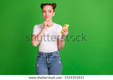 Photo of minded lady hold cellphone finger chin look empty space think wear white t-shirt isolated green background