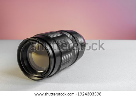 Vintage soviet manual telephoto prime lens with focal length of 200mm close up shot on white and pink background, soft focus