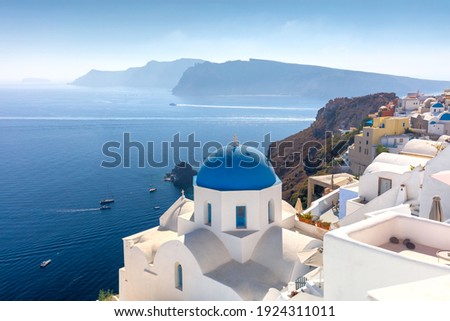 Famous view of Oia town cityscape at Santorini island in Greece. Traditional blue dome and white houses. Greece, Aegean sea. Famous European destination Royalty-Free Stock Photo #1924311011