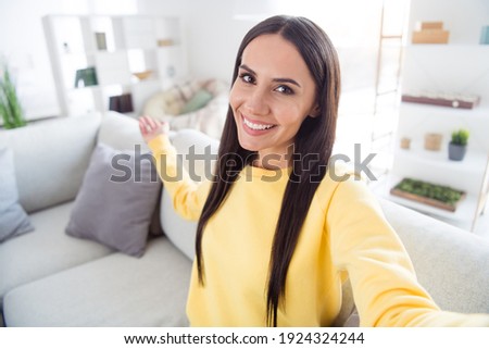 Photo of young cheerful woman happy positive smile indicate hand empty space invite welcome make selfie indoors