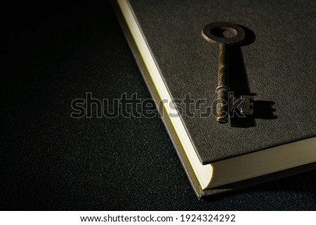 Vintage key and hardback book on dark background