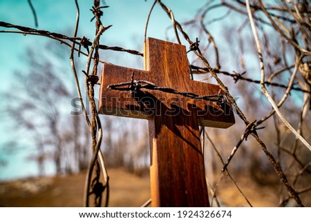 The barbed wire and the wooden cross.